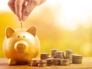 a person putting a coin into a piggy bank.