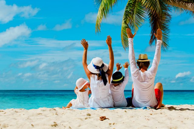 a group of people sitting on top of a sandy beach.